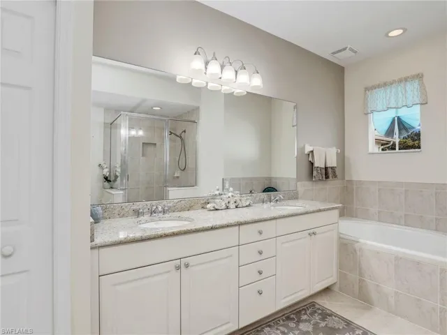 Primary Bathroom with  dual sink vanity, independent shower and bath, and tile patterned flooring