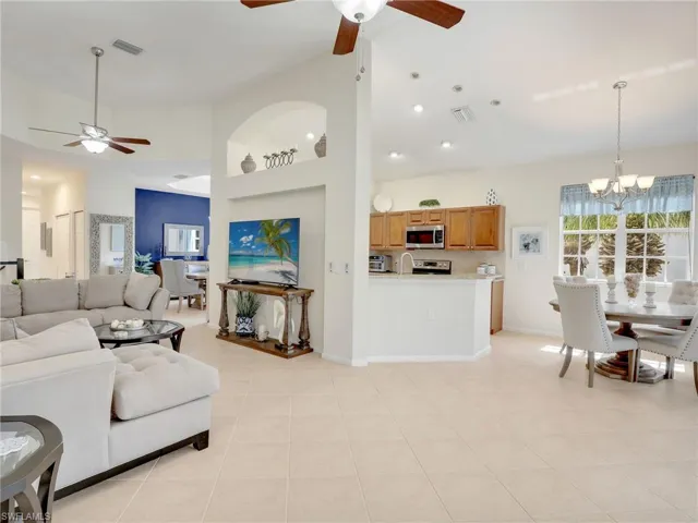 Living room featuring  a high ceiling, light tile patterned flooring, and ceiling fan with notable chandelier