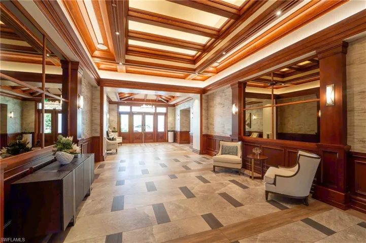 Community lobby with a wainscoted wall, crown molding, a decorative wall, and coffered ceiling