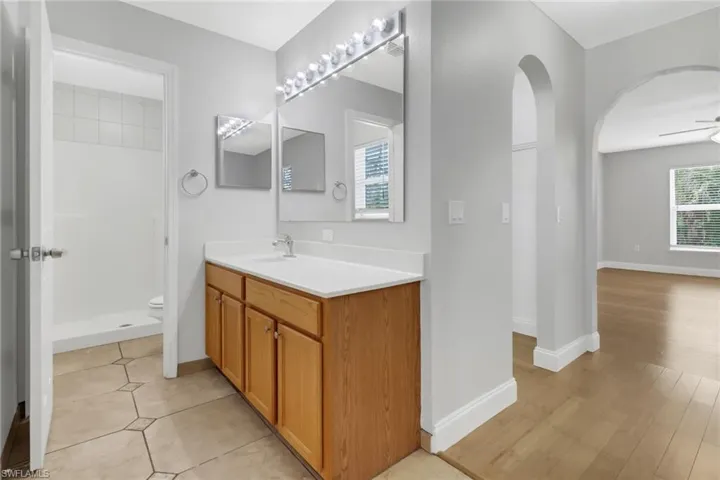 Bathroom featuring ceiling fan, oversized vanity, toilet, and tile floors