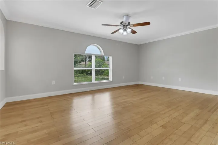 Spare room featuring ceiling fan, light wood-type flooring, and crown molding