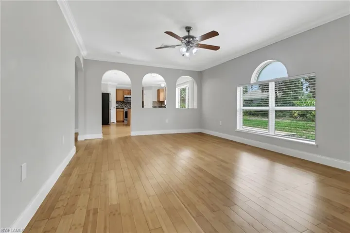Unfurnished living room featuring ceiling fan, ornamental molding, and light hardwood / wood-style flooring