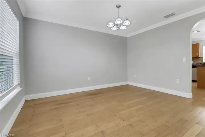 Unfurnished room with an inviting chandelier, ornamental molding, and light hardwood / wood-style floors