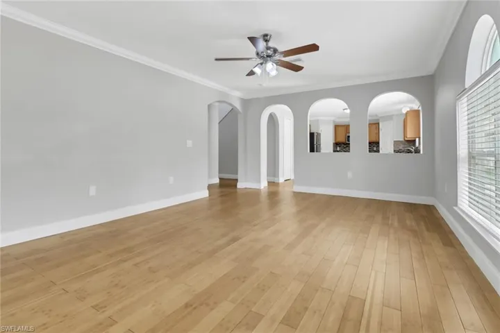 Unfurnished living room featuring ceiling fan, ornamental molding, and light hardwood / wood-style floors