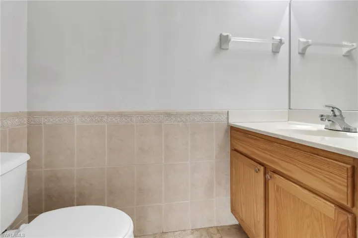 Bathroom with tile walls, tile floors, oversized vanity, and toilet