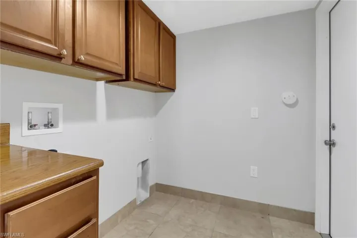 Laundry room featuring washer hookup, cabinets, and light tile floors