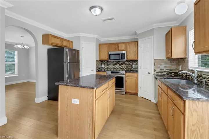 Kitchen featuring light hardwood / wood-style flooring, a kitchen island, stainless steel appliances, tasteful backsplash, and sink