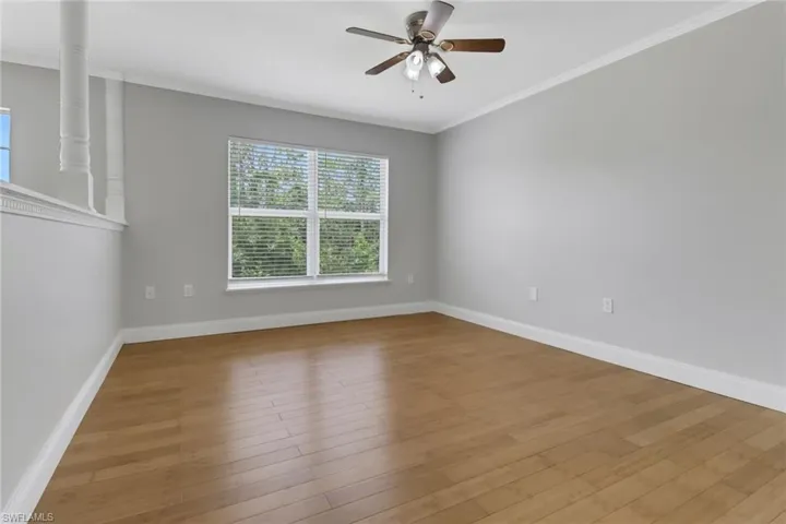 Unfurnished room featuring ceiling fan, light wood-type flooring, and ornamental molding