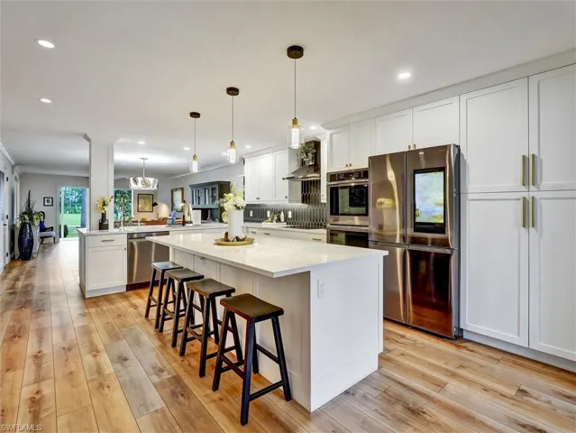 Kitchen with stainless steel appliances, white cabinetry, a peninsula, and a breakfast bar area