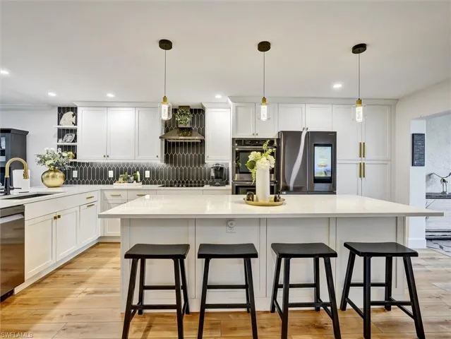 Kitchen featuring white cabinets, a kitchen bar, hanging light fixtures, and a kitchen island