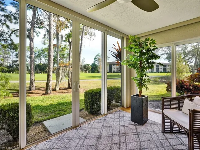 Sunroom with a ceiling fan and golf course view