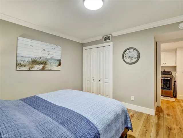 Bedroom featuring light wood-type flooring, crown molding, and a closet