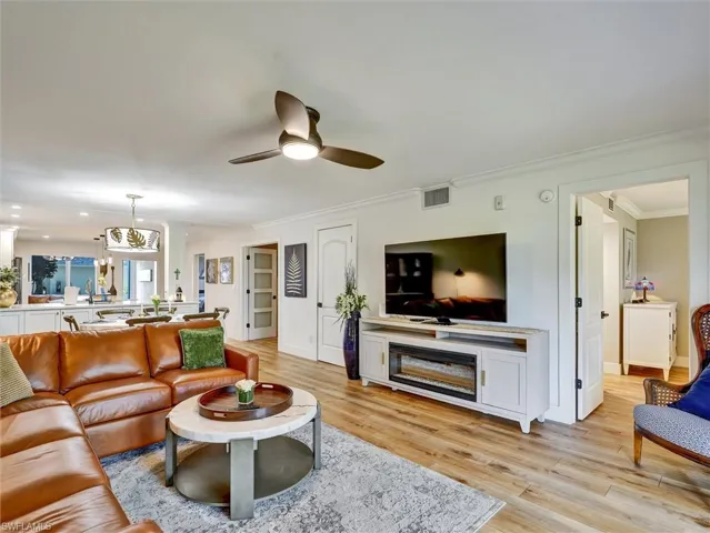 Living room with ornamental molding, light wood-type flooring, and a ceiling fan