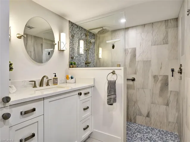 Bathroom featuring vanity and a marble finish shower