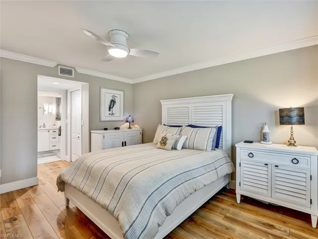 Bedroom with light wood-type flooring, crown molding, a ceiling fan, and ensuite bath