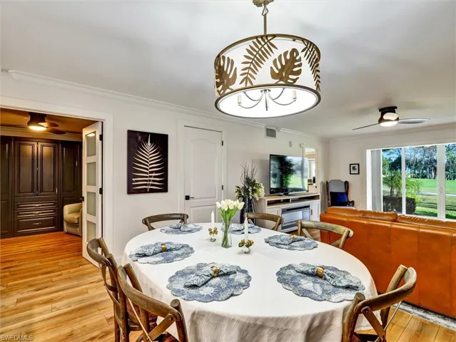 Dining room with a ceiling fan, crown molding, and light wood-style floors