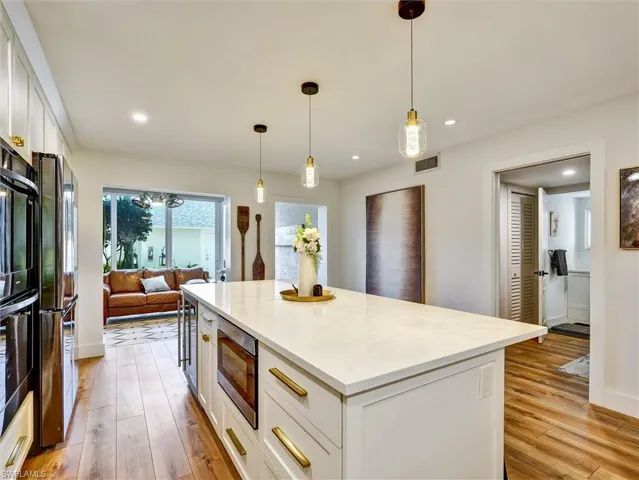Kitchen with white cabinets, light wood finished floors, and a kitchen island