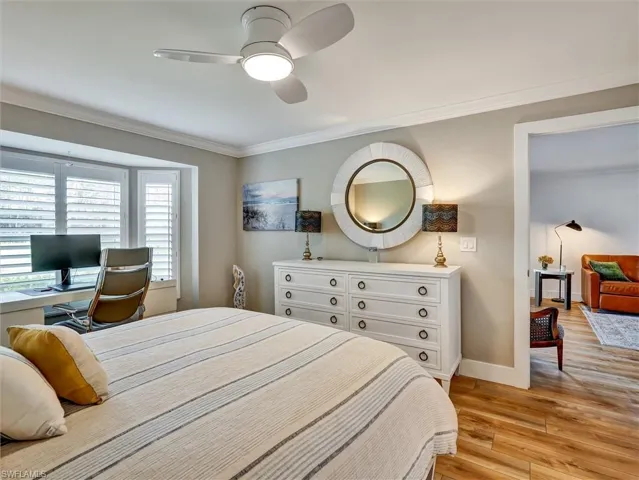 Bedroom with light wood finished floors, a ceiling fan, and ornamental molding