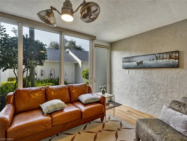 Living room featuring a textured wall, wood finished floors, a textured ceiling, and suspended lighting