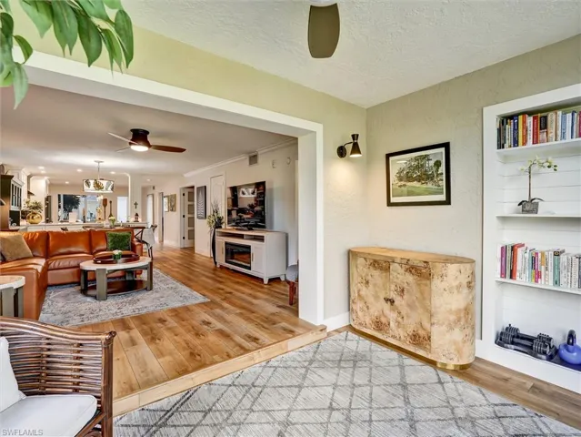 Living area featuring ceiling fan, light wood-style floors, a textured ceiling, and a textured wall