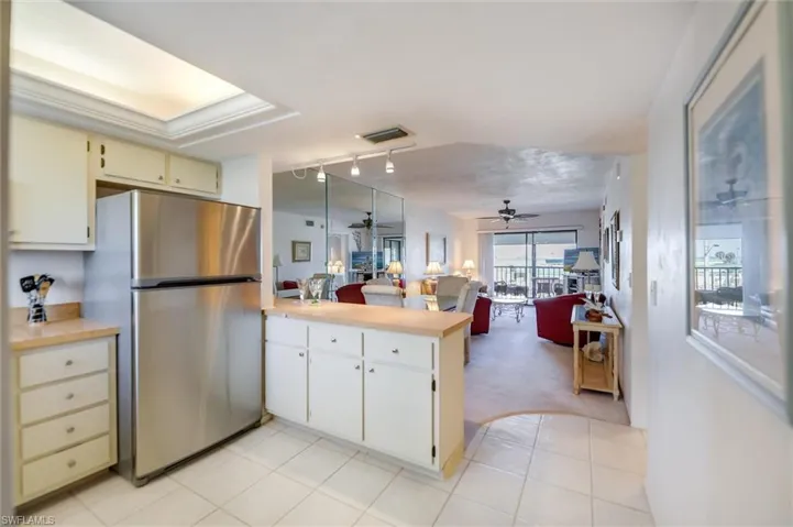Kitchen featuring ceiling fan, stainless steel refrigerator, kitchen peninsula, and light tile patterned flooring