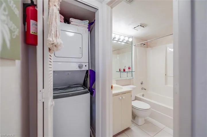 Full bathroom with tile patterned floors, toilet, shower / tub combination, vanity, and stacked washing maching and dryer