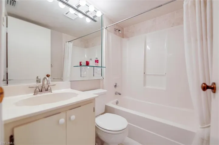Full bathroom with vanity, shower / bath combo with shower curtain, and toilet