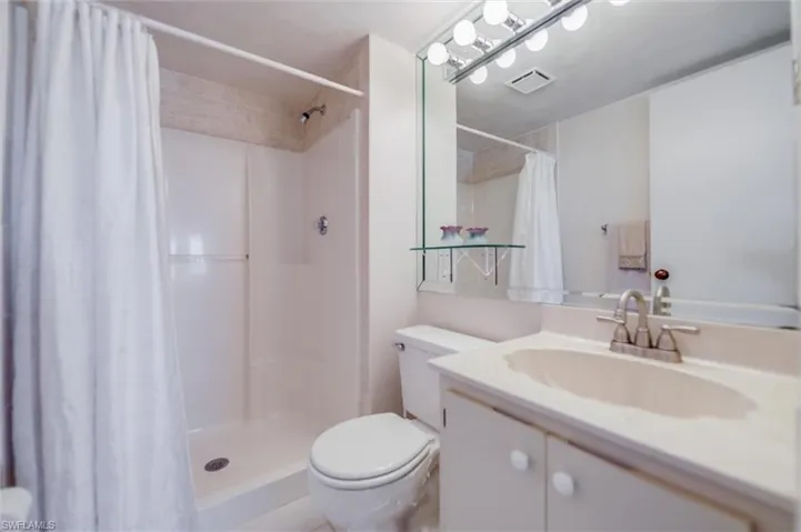 Bathroom with toilet, vanity, and a shower with curtain