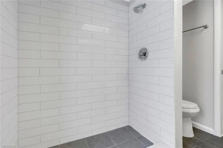Bathroom featuring a tile shower, hardwood / wood-style flooring, and toilet