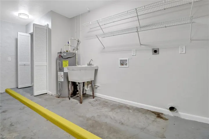 Laundry area with electric water heater, hookup for a washing machine, and electric dryer hookup