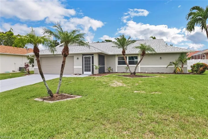 Single story home with a garage and a front lawn