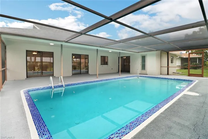 View of swimming pool with glass enclosure and a patio area