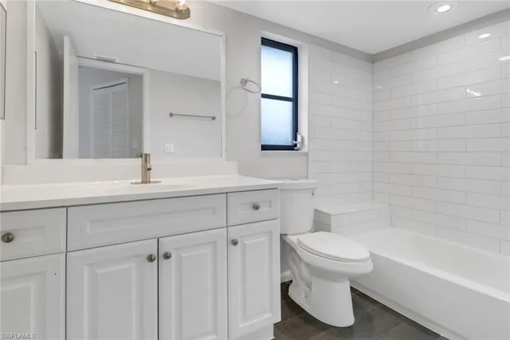 Full bathroom with vanity, tile patterned flooring, tiled shower / bath combo, and toilet