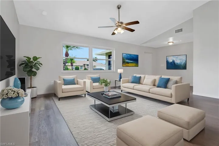 Living room with ceiling fan, hardwood / wood-style flooring, and vaulted ceiling