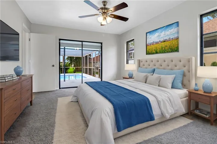Bedroom with multiple windows, light colored carpet, access to exterior, and ceiling fan