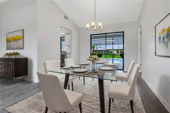 Dining space with dark hardwood / wood-style flooring, lofted ceiling, and a chandelier