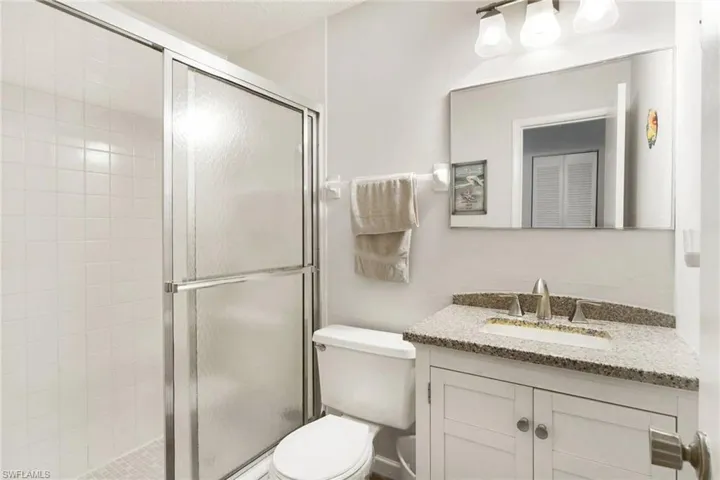 Bathroom featuring toilet, vanity, and walk in shower