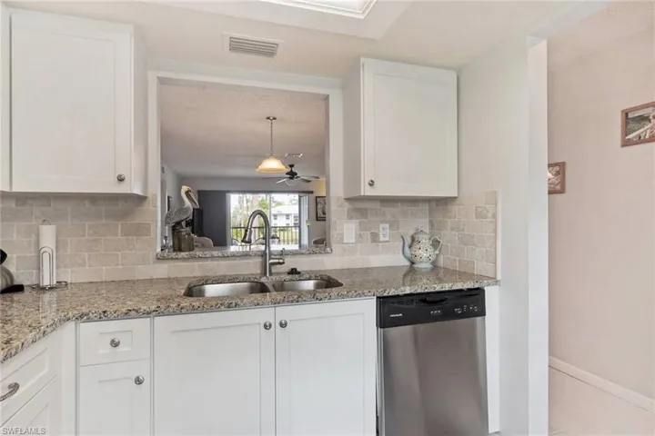 Kitchen featuring ceiling fan, backsplash, dishwasher, white cabinets, and sink