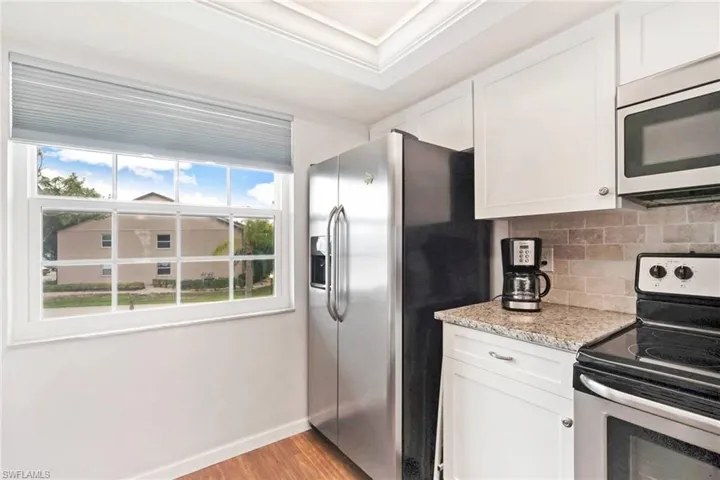 Kitchen featuring white cabinets, appliances with stainless steel finishes, light hardwood / wood-style flooring, and crown molding