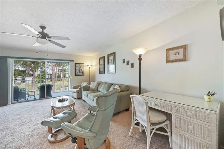 Carpeted living room featuring a textured ceiling and ceiling fan