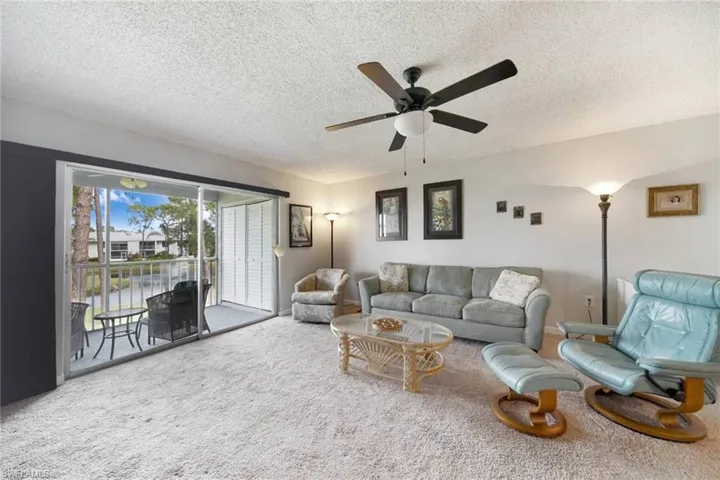 Carpeted living room featuring a textured ceiling and ceiling fan