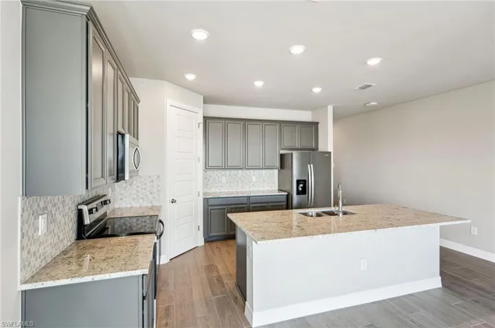 Kitchen with appliances with stainless steel finishes, sink, an island with sink, and decorative backsplash