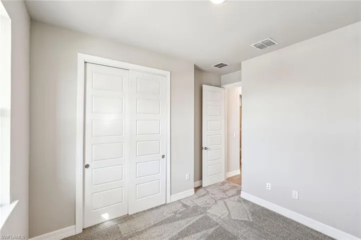 Unfurnished bedroom with light carpet and a closet