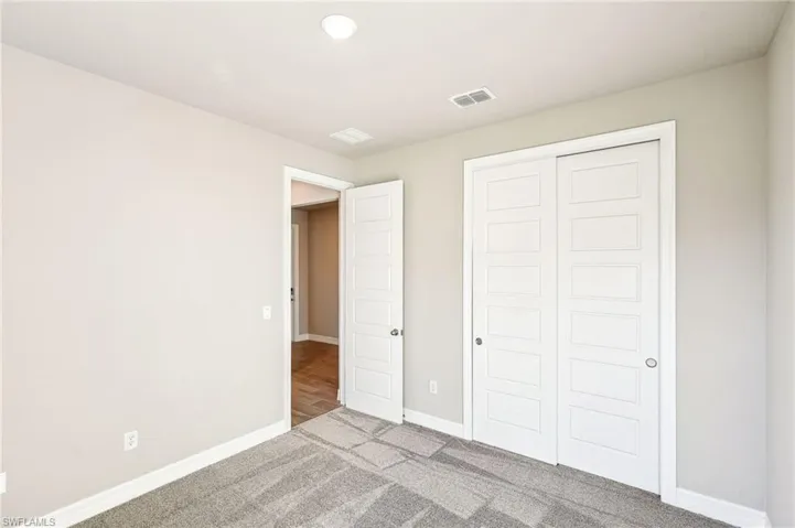 Unfurnished bedroom featuring light colored carpet and a closet