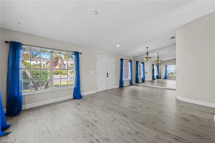 Unfurnished living room with light wood-style flooring, lofted ceiling, and a chandelier