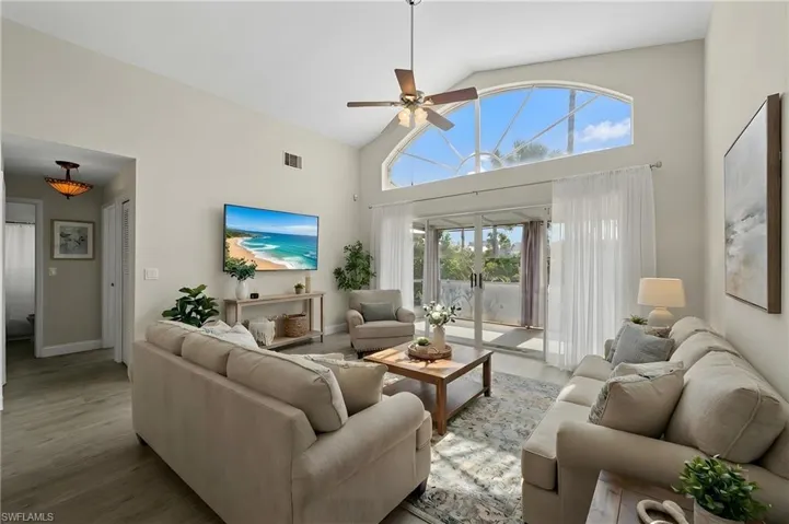 Living room with ceiling fan, wood finished floors, and vaulted ceiling
