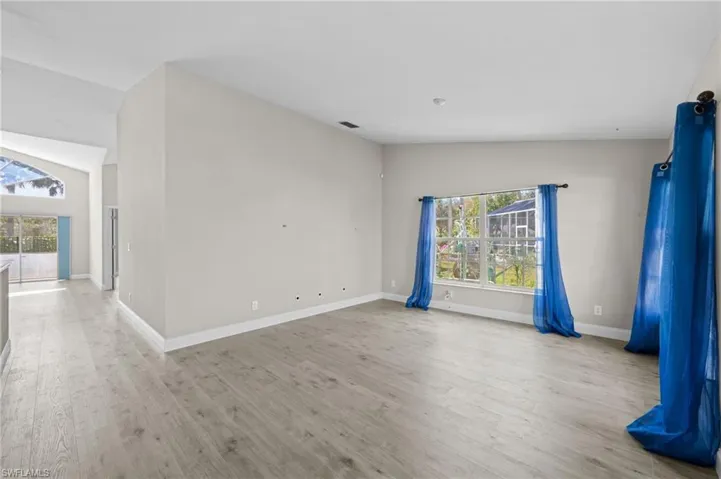 Spare room featuring light wood finished floors and vaulted ceiling
