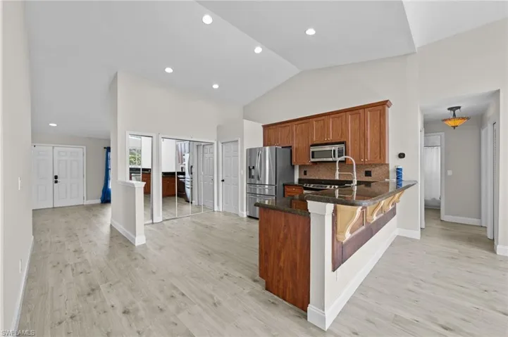 Kitchen featuring wood finish cabinetry, a kitchen bar, stainless steel appliances, a peninsula, and dark stone countertops