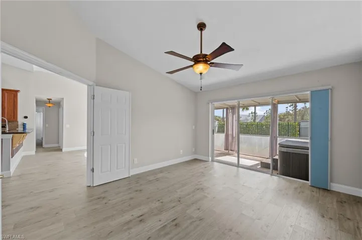 Empty room with ceiling fan, light wood-style floors, and lofted ceiling