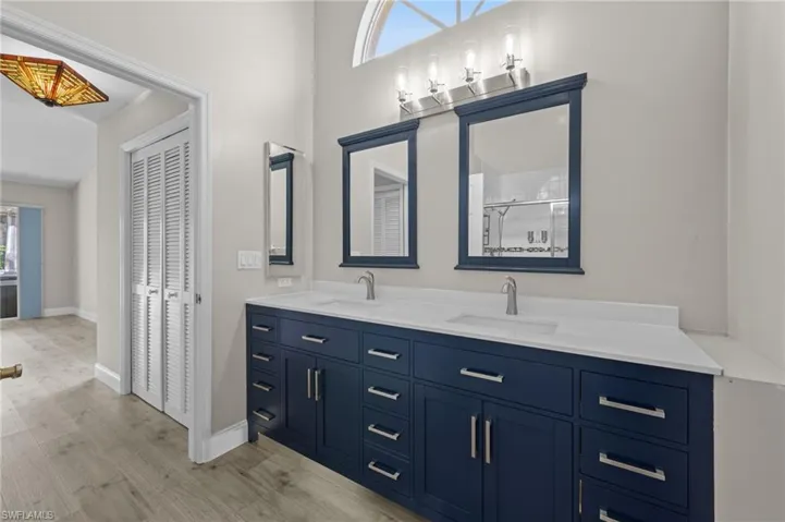 Bathroom with plenty of natural light, double vanity, light wood-style floors, and a closet